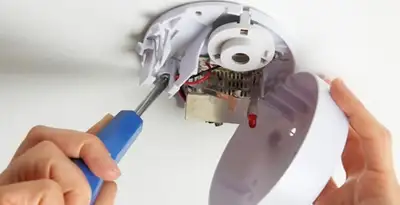 Certified technician wiring smoke detector during installation in Phoenix, AZ